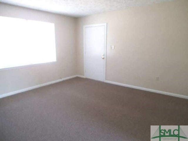 carpeted spare room featuring baseboards