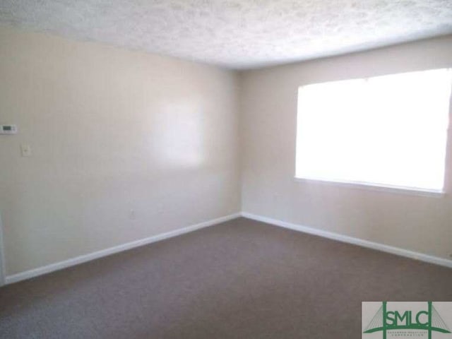 spare room featuring carpet flooring, a textured ceiling, and baseboards