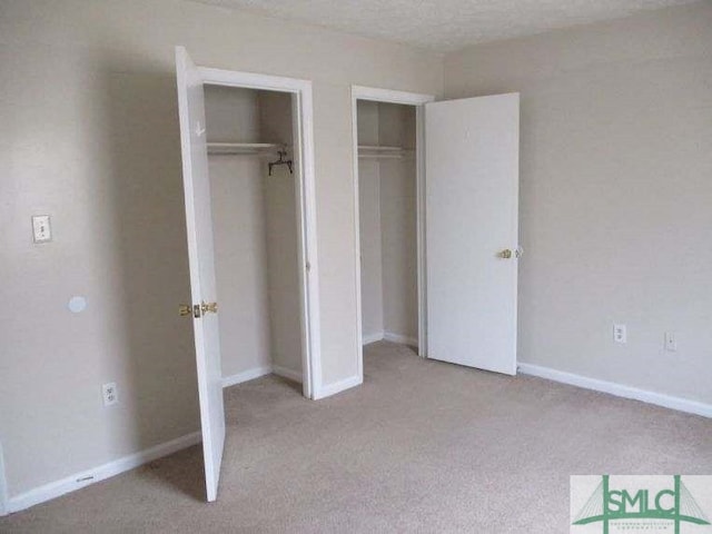 unfurnished bedroom featuring carpet, two closets, and baseboards