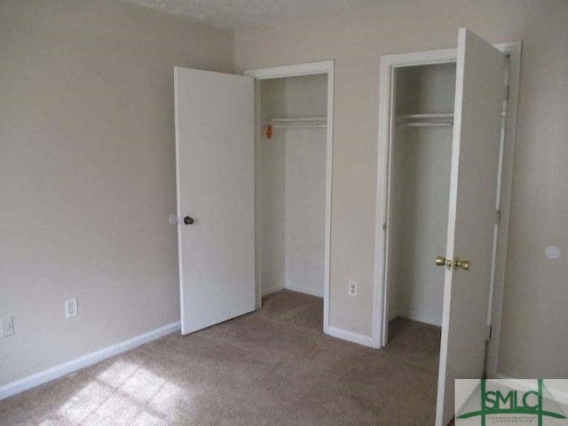 unfurnished bedroom with carpet floors, baseboards, and multiple closets