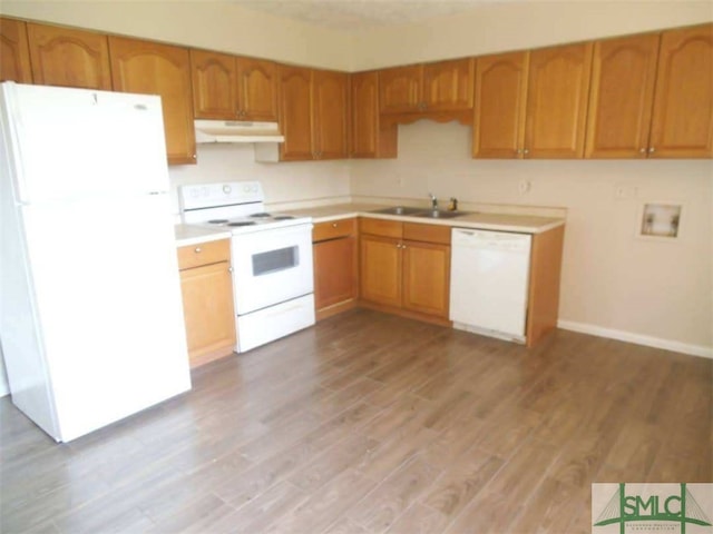 kitchen featuring white appliances, light wood-style flooring, light countertops, under cabinet range hood, and a sink