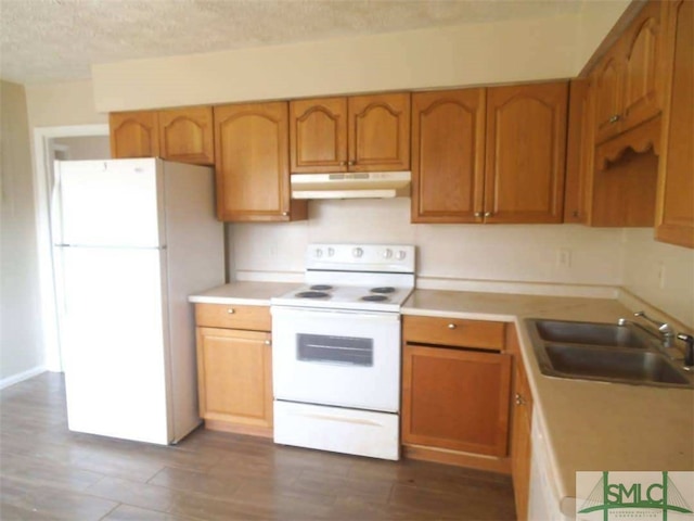 kitchen featuring under cabinet range hood, white appliances, a sink, light countertops, and brown cabinetry