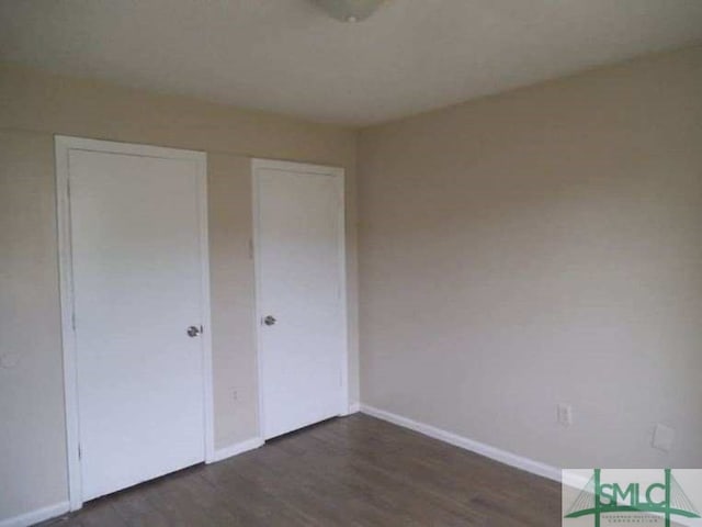 unfurnished bedroom with dark wood-style floors, baseboards, and a closet