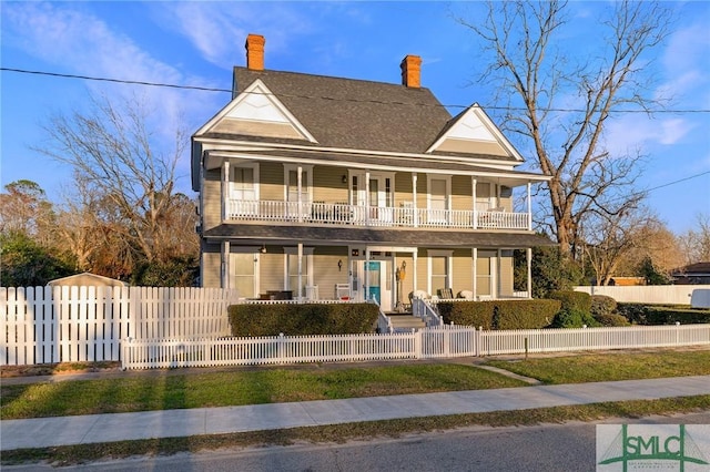 view of front of property featuring a fenced front yard, a chimney, covered porch, a gate, and a balcony