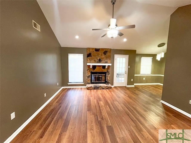 unfurnished living room with visible vents, a stone fireplace, baseboards, and wood finished floors