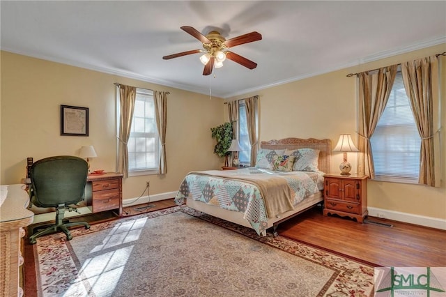 bedroom with baseboards, wood finished floors, and crown molding