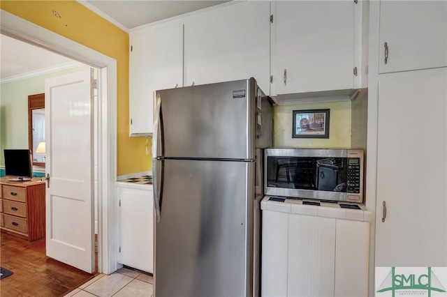 kitchen with wood finished floors, white cabinetry, light countertops, appliances with stainless steel finishes, and crown molding