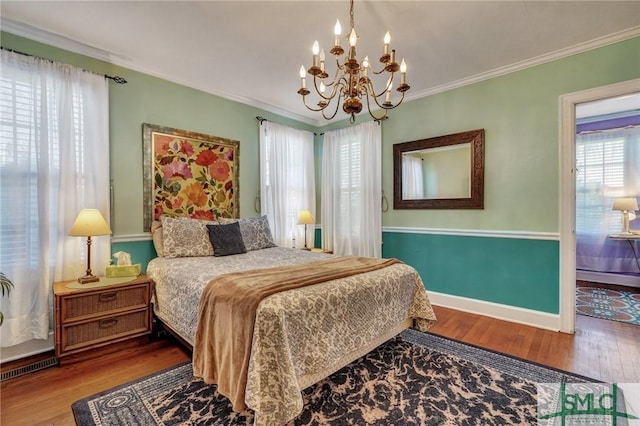 bedroom featuring a notable chandelier, baseboards, ornamental molding, and wood finished floors