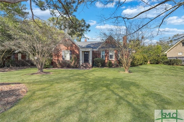 view of front of property with brick siding, a chimney, and a front yard