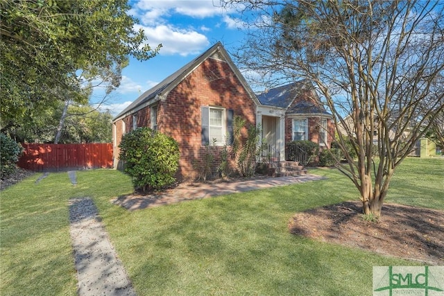 view of front facade with brick siding, fence, and a front lawn