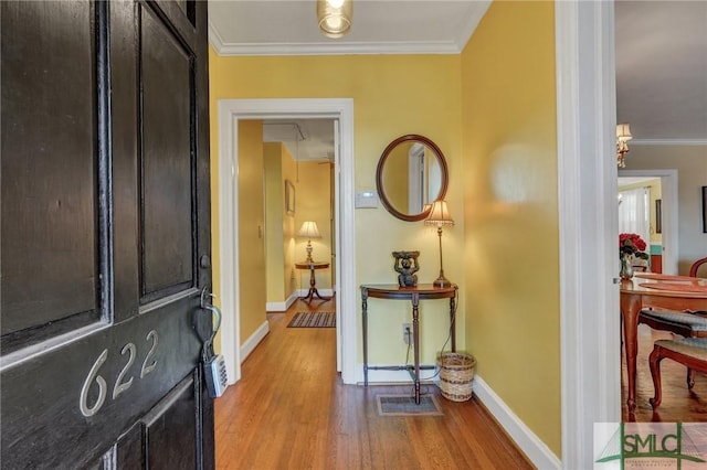 entrance foyer with baseboards, ornamental molding, and wood finished floors