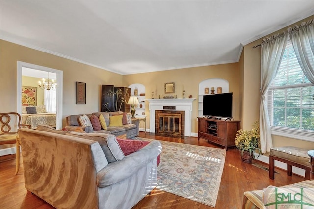 living room featuring ornamental molding, a tiled fireplace, wood finished floors, and a notable chandelier