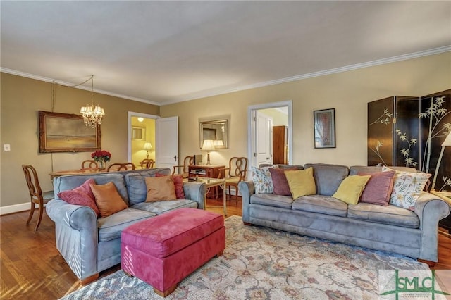 living area with a chandelier, ornamental molding, baseboards, and wood finished floors