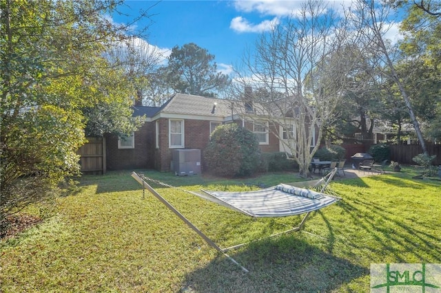 view of yard with fence, central AC, and a patio