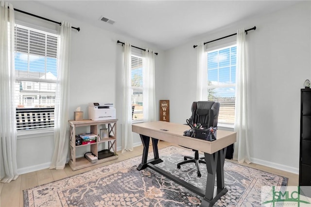 office space with light wood finished floors, plenty of natural light, visible vents, and baseboards