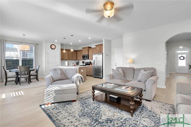 living room featuring a healthy amount of sunlight, light wood-style flooring, arched walkways, and recessed lighting