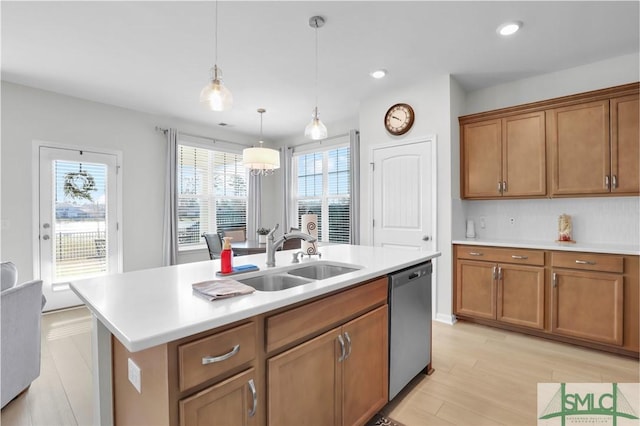 kitchen with light countertops, stainless steel dishwasher, a sink, and brown cabinets