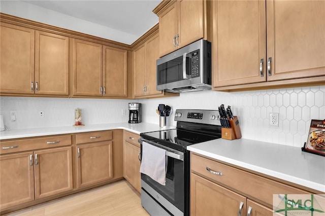 kitchen featuring light countertops, appliances with stainless steel finishes, brown cabinets, and decorative backsplash