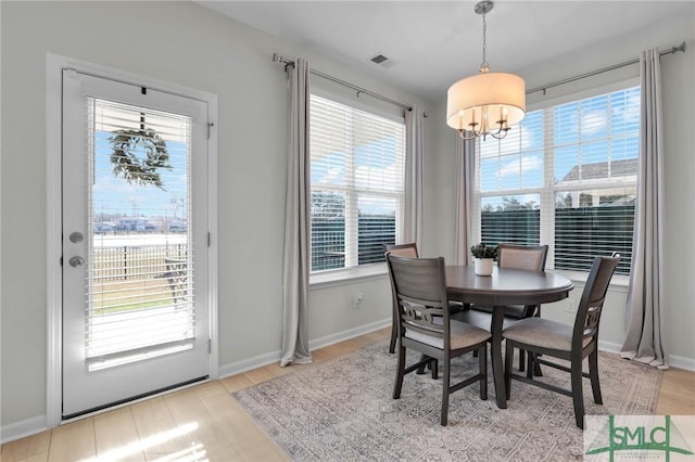 dining room featuring light wood-style floors, a healthy amount of sunlight, and baseboards