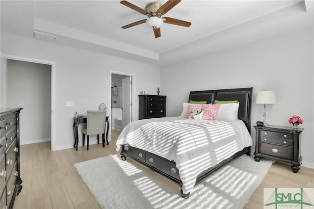 bedroom with light wood-type flooring, a raised ceiling, visible vents, and baseboards