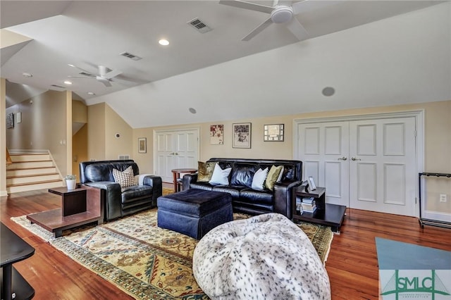 living area with lofted ceiling, ceiling fan, wood finished floors, visible vents, and stairway