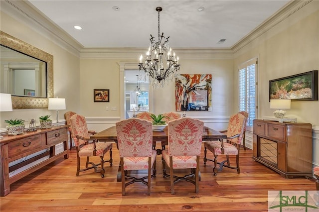 dining space featuring ornamental molding, visible vents, light wood-style flooring, and an inviting chandelier