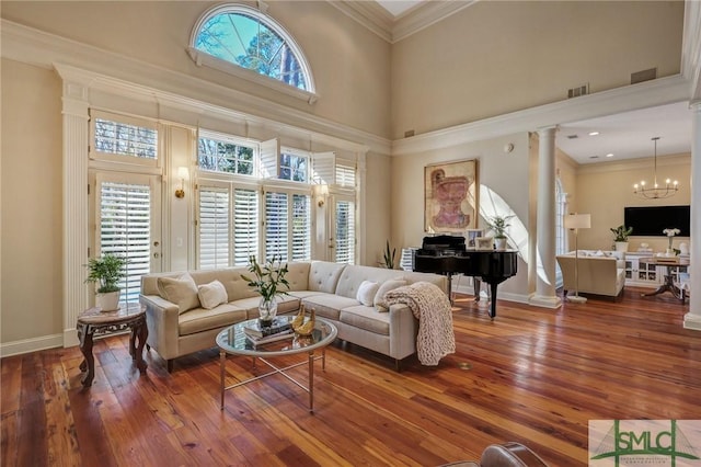 living area featuring ornamental molding, a towering ceiling, visible vents, and ornate columns