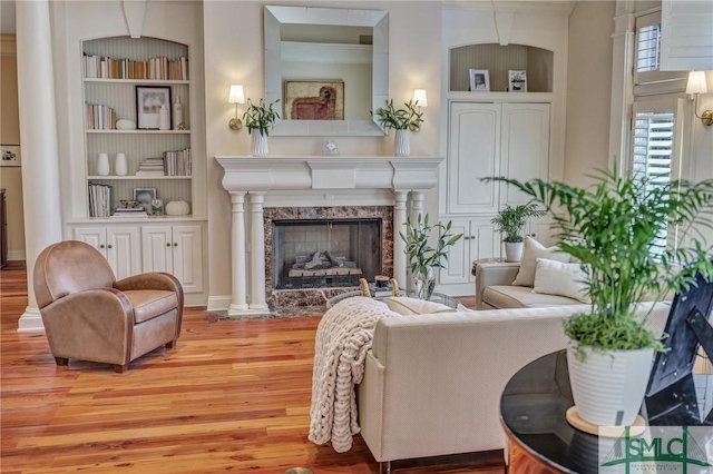 living room featuring built in shelves, a fireplace, and wood finished floors