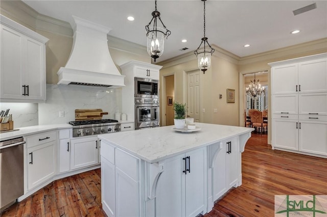 kitchen with visible vents, a kitchen island, appliances with stainless steel finishes, premium range hood, and white cabinetry