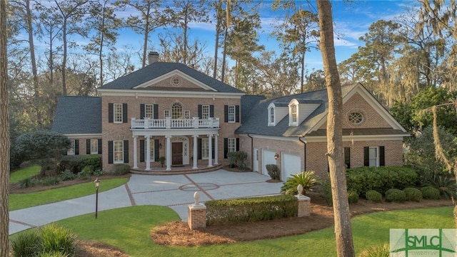 view of front of home with brick siding, a front yard, a balcony, a garage, and driveway