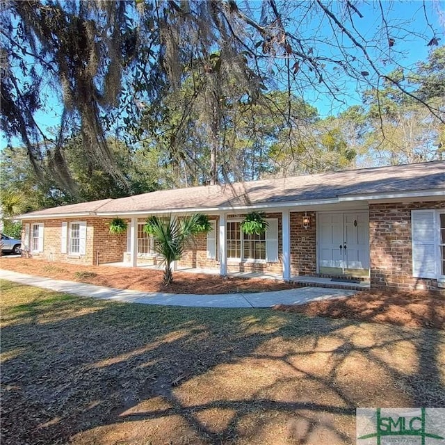 ranch-style home featuring covered porch and brick siding