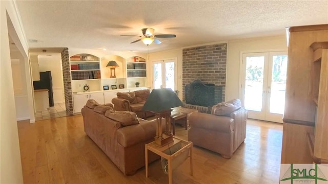 living area with light wood-style flooring, a wealth of natural light, french doors, and a textured ceiling