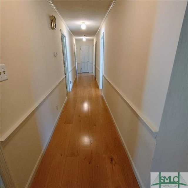 hallway with baseboards, light wood-type flooring, and crown molding