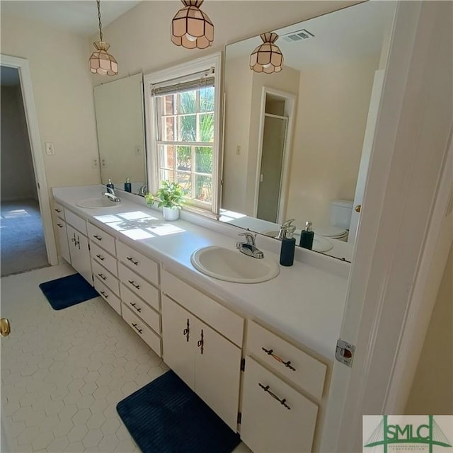 bathroom featuring double vanity, a stall shower, a sink, and visible vents