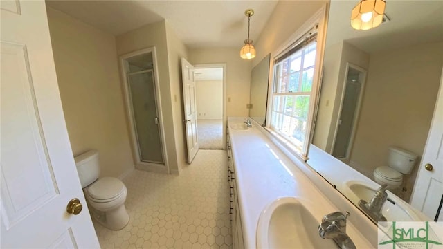 bathroom featuring double vanity, a stall shower, a sink, and toilet