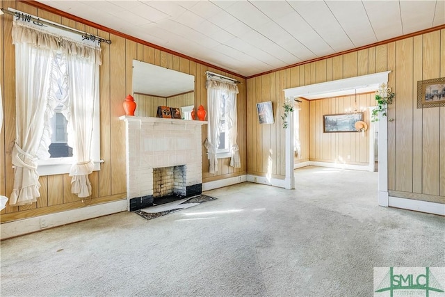 unfurnished living room with carpet floors, crown molding, wood walls, and a fireplace with flush hearth