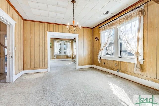 unfurnished dining area with carpet floors, visible vents, ornamental molding, and a chandelier