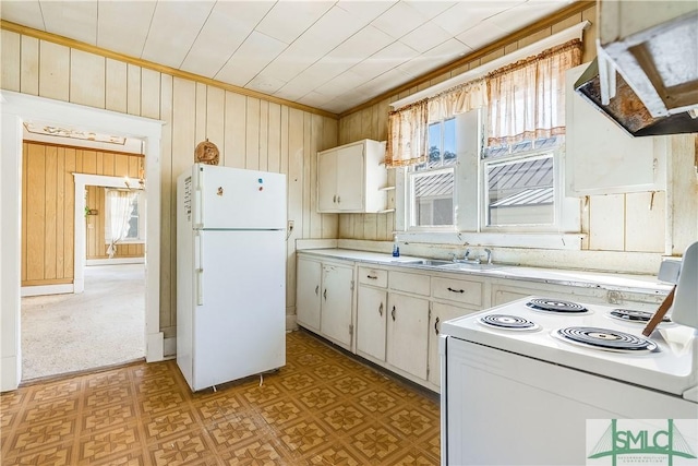 kitchen with light floors, light countertops, a sink, wooden walls, and white appliances