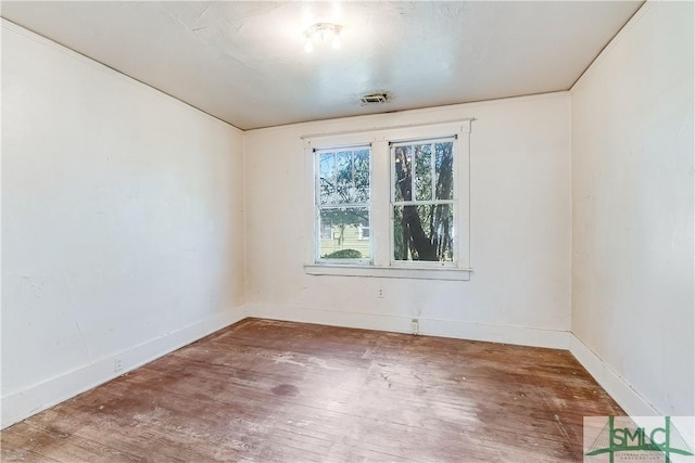 spare room with visible vents, baseboards, and wood finished floors