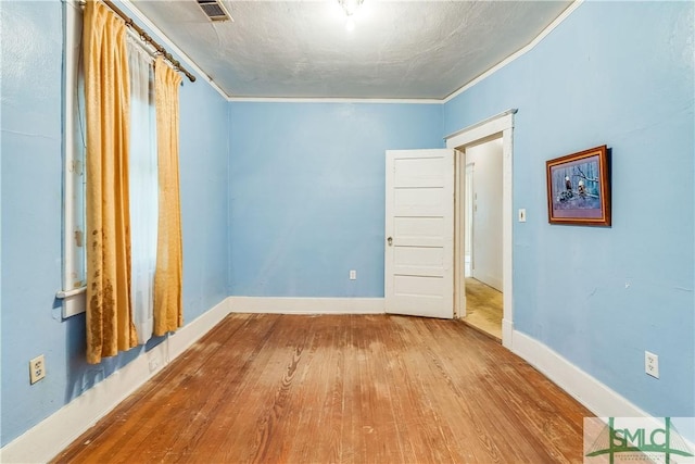 unfurnished room featuring visible vents, crown molding, baseboards, and wood finished floors