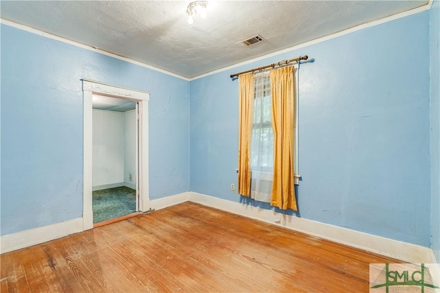 spare room featuring visible vents, crown molding, a textured ceiling, and wood finished floors