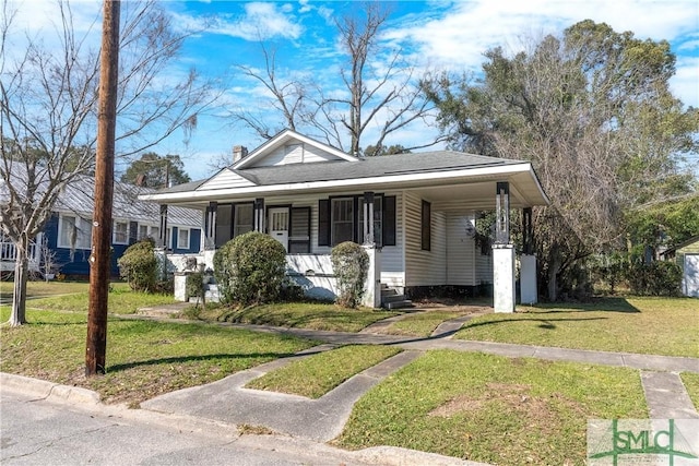 bungalow-style home with a carport, a front yard, roof with shingles, and a chimney