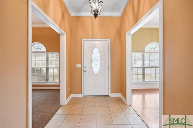 foyer entrance with light tile patterned floors, light colored carpet, a wealth of natural light, and crown molding