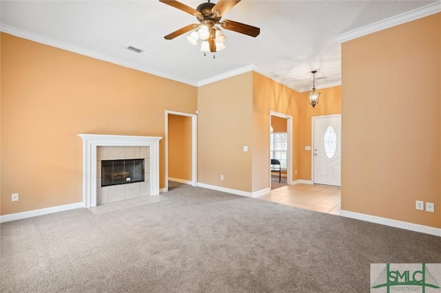 unfurnished living room featuring carpet, crown molding, visible vents, a tiled fireplace, and baseboards