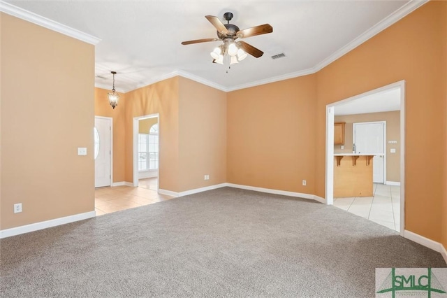 spare room with a ceiling fan, light colored carpet, crown molding, and visible vents