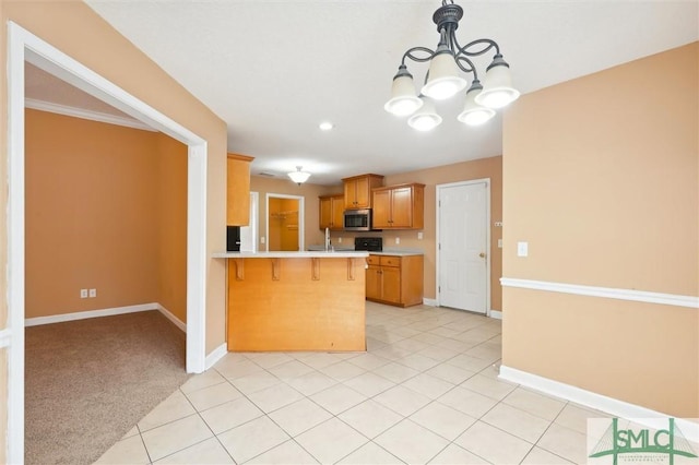 kitchen featuring baseboards, stainless steel microwave, a peninsula, light countertops, and a kitchen bar