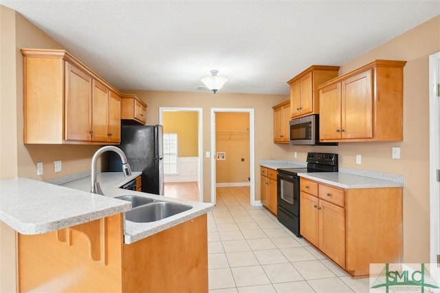 kitchen with a peninsula, black appliances, light countertops, and a sink