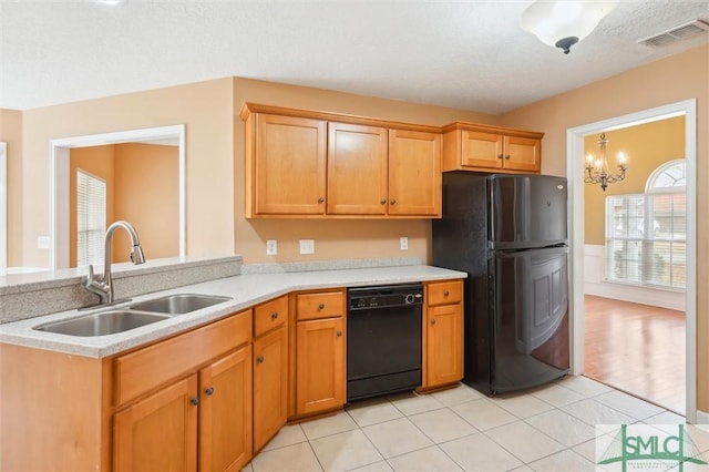 kitchen featuring light tile patterned floors, visible vents, light countertops, black appliances, and a sink