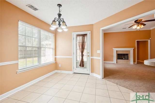 interior space with visible vents, light colored carpet, a textured ceiling, a fireplace, and light tile patterned flooring