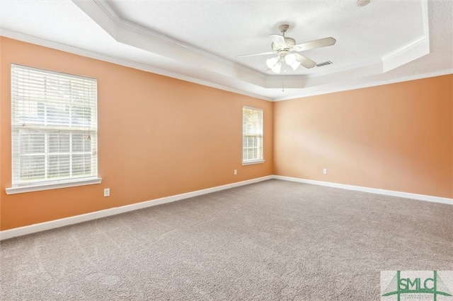 carpeted empty room featuring baseboards, a tray ceiling, and crown molding